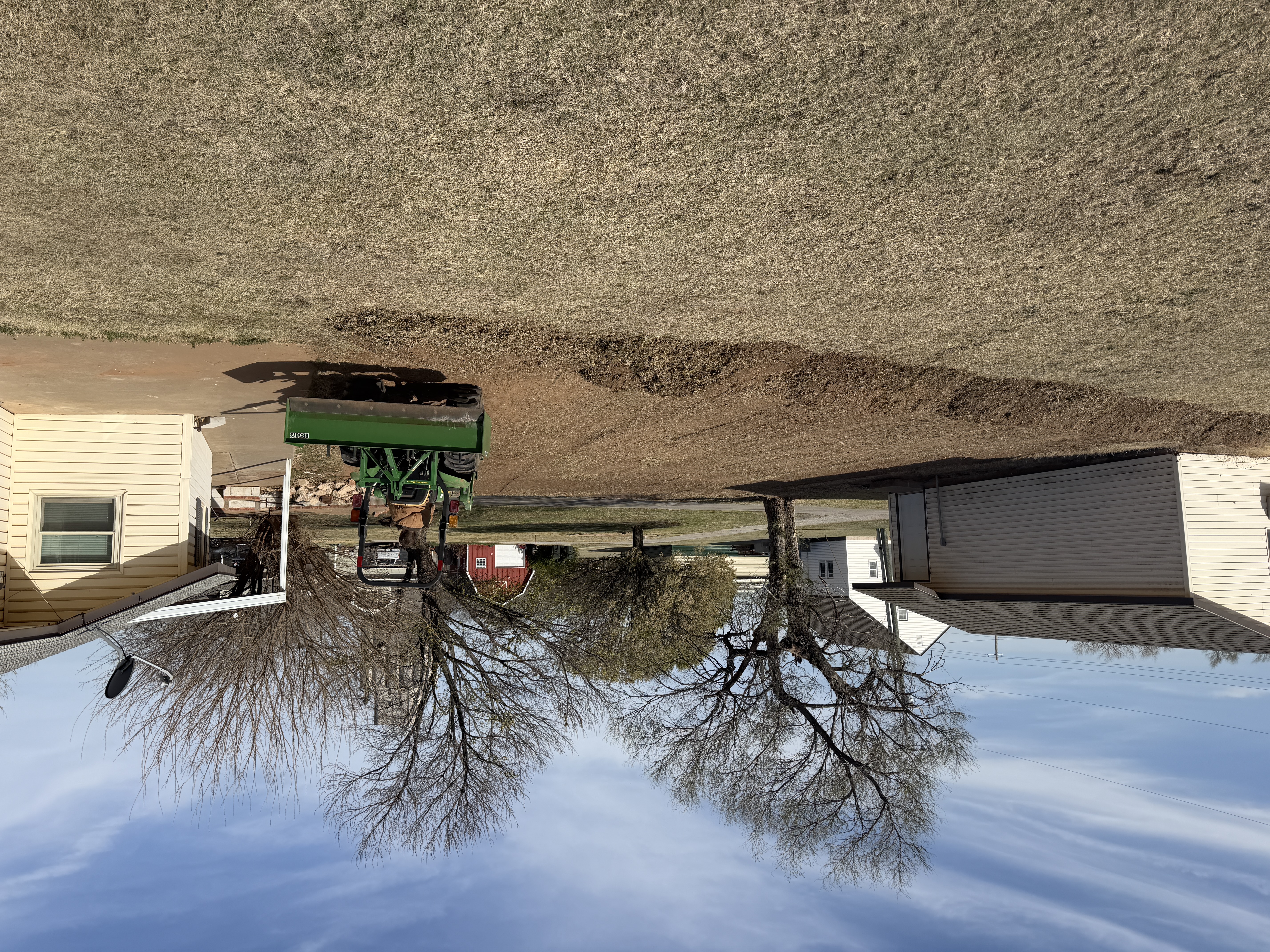 Man on a tractor leveling dirt next to a house