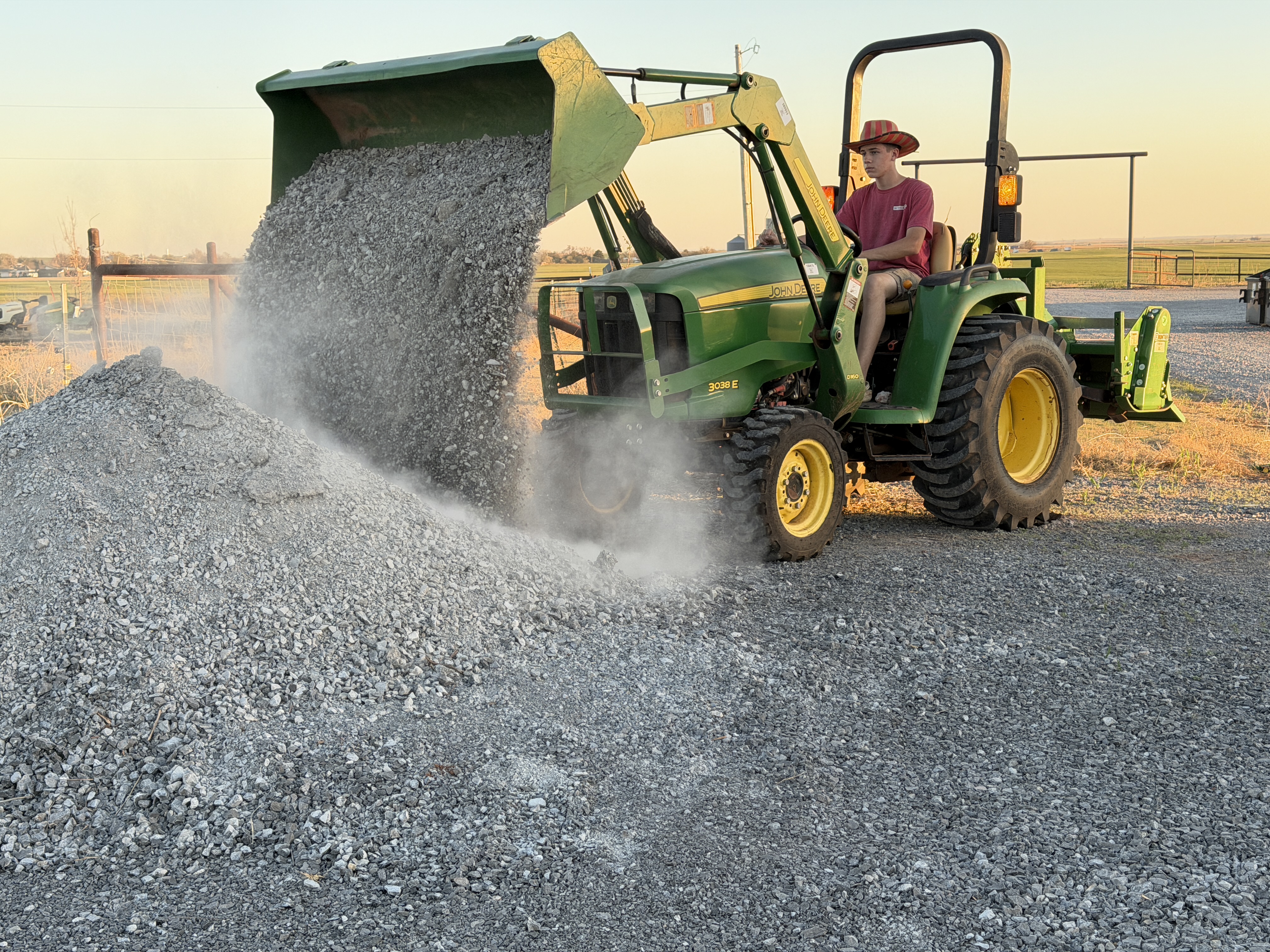 John Deere tractor dumping gravel onto a pile