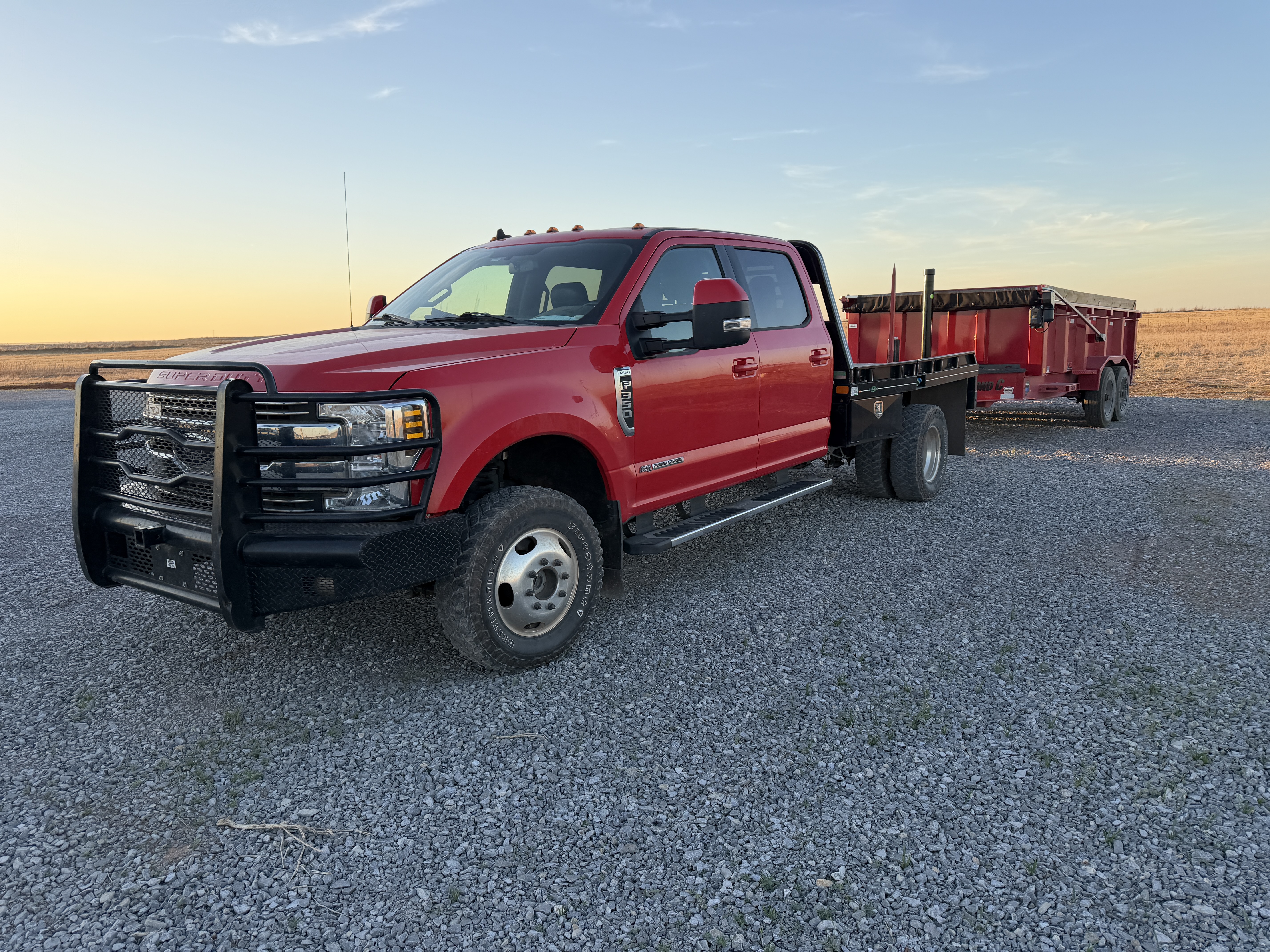 Red truck pulling an empty red dump trailer
